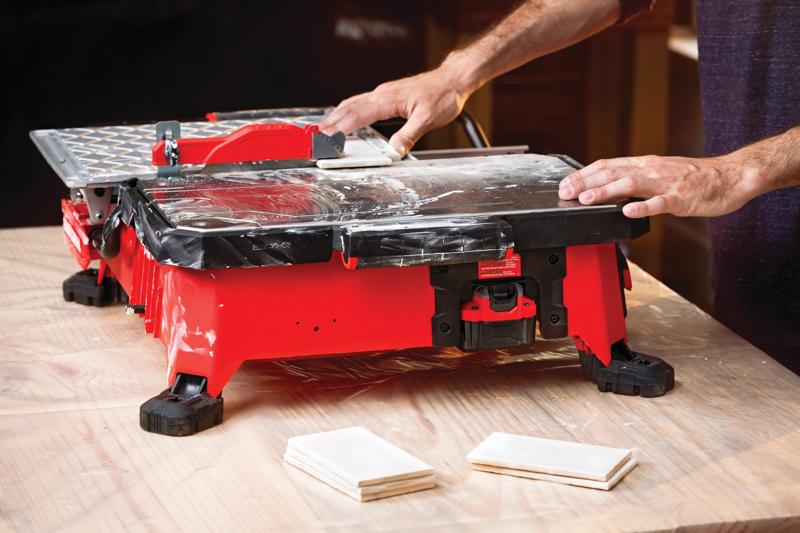 20 volt 7 inch cordless compact wet tile saw being used by a person to cut a tile.
