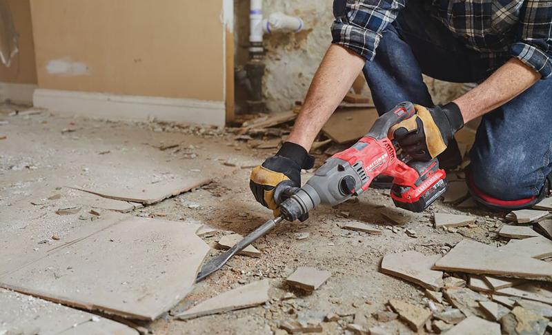 Man with gloves, respirator and safety glasses using the CRAFSTMAN V20 Brushless RP 7/8 inch SDS plus Rotary Hammer with to remove tile flooring.