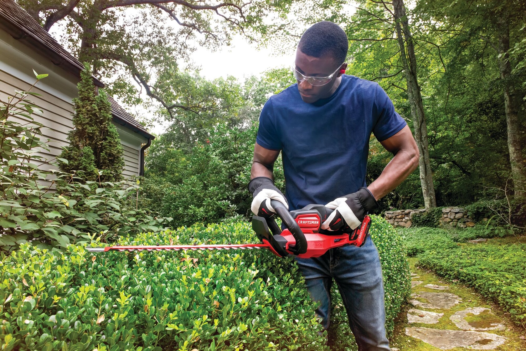 Cordless 22 inch hedge trimmer kit 2 ampere hours being used to level bushes sides.
