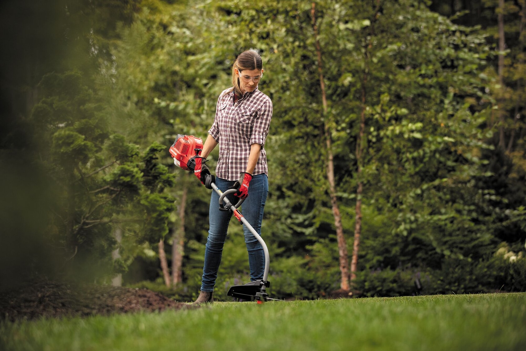 W C 2200 weedwacker 25 C C 2 cycle 17 inch attachment capable curved shaft gas trimmer trimming grass being used by a person to trim grass.
