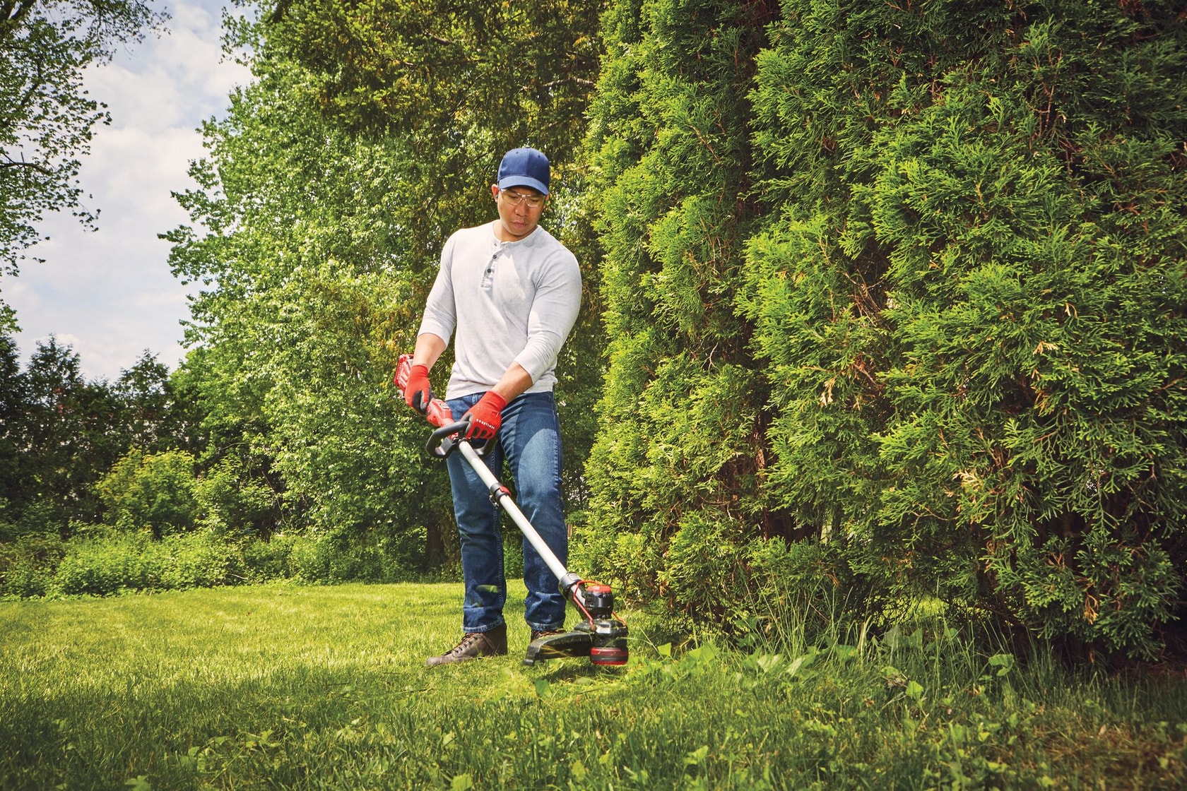 20 volt cordless 13 inch weedwacker string trimmer edger with push button feed being used by a person to trim grass outdoors.
