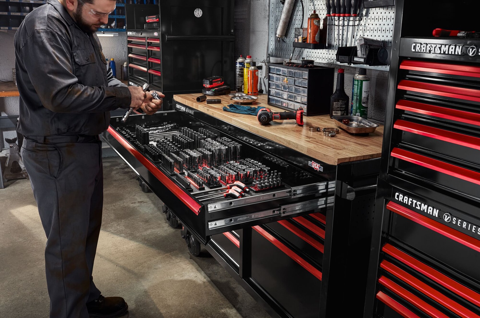 Mechanic working in automotive shop filled with various CRAFTSMAN V-Series™ storage and tools